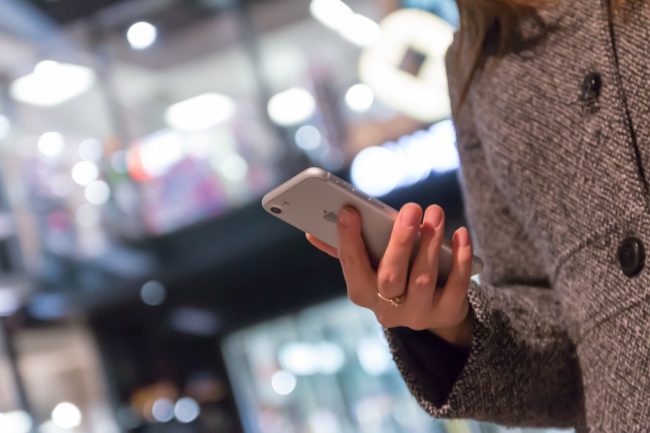 Instagram für Unternehmen - Frau unterwegs stehend mit Smartphone in der Hand
