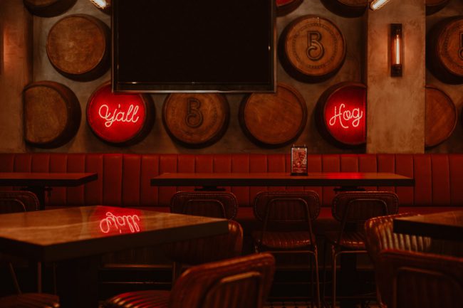 Pub mit leeren Stühlen und Tischen, Bierfässern an der Wand und einen großen Screen
